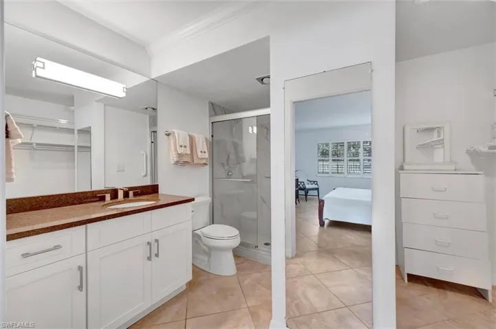 Ensuite bathroom with vanity, a stall shower, light tile patterned floors, and a closet