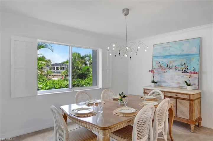 Dining space featuring ornamental molding, a chandelier, and light tile patterned floors