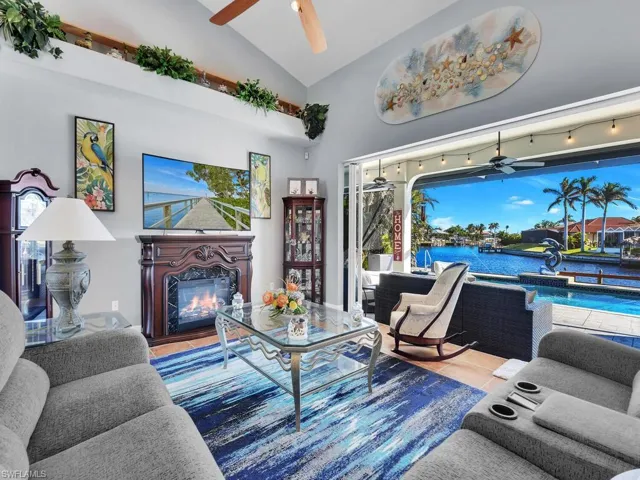 Living room featuring a fireplace, high vaulted ceiling, track lighting, and tile patterned floors