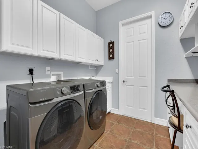 Laundry room with dark tile patterned floors, cabinets, and independent washer and dryer