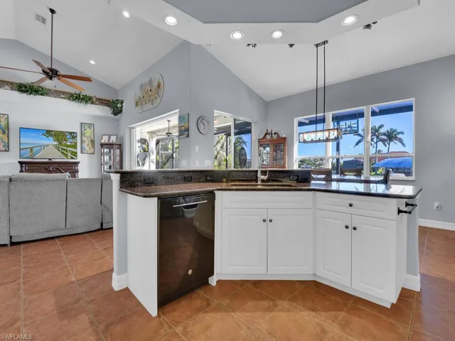 Kitchen with hanging light fixtures, ceiling fan, black dishwasher, light tile patterned flooring, and white cabinetry