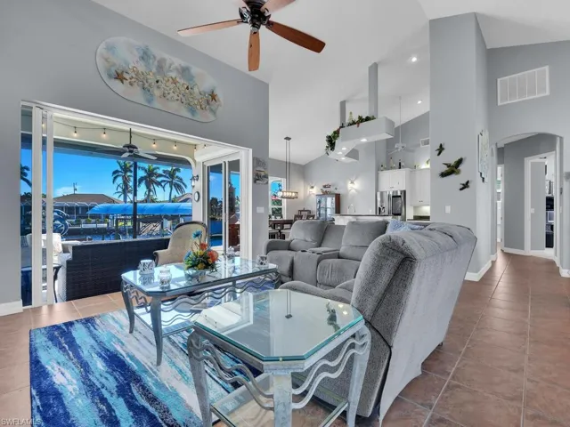 Living room with high vaulted ceiling, tile patterned floors, and ceiling fan