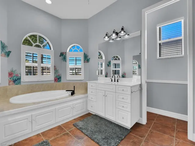 Bathroom featuring tile patterned floors, a bathtub, vanity, and a high ceiling