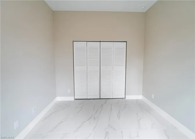 Unfurnished bedroom featuring a closet and light marble finish floors
