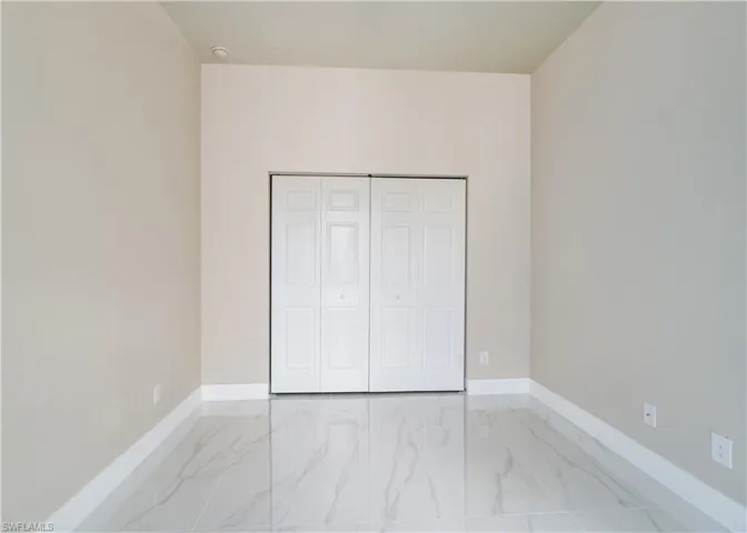 Unfurnished bedroom with light marble finish floors and a closet