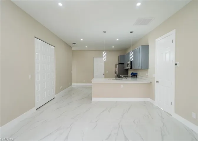 Kitchen featuring a peninsula, electric range oven, hanging light fixtures, recessed lighting, and light stone countertops