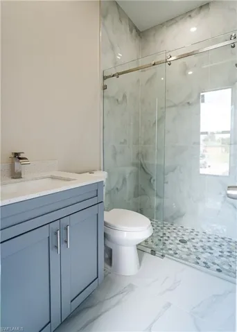 Bathroom featuring a marble finish shower and vanity