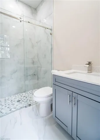 Full bath featuring a marble finish shower and vanity