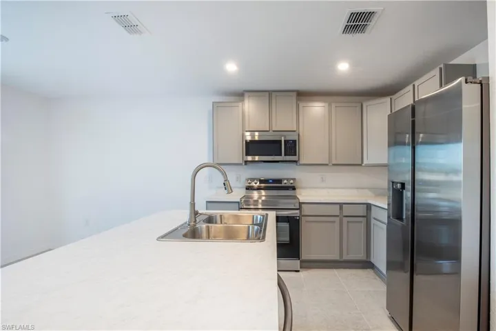 Kitchen featuring appliances with stainless steel finishes, gray cabinets, sink, and light tile patterned floors