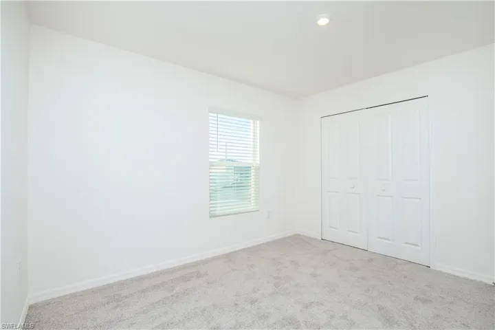 Unfurnished bedroom with light carpet and a closet