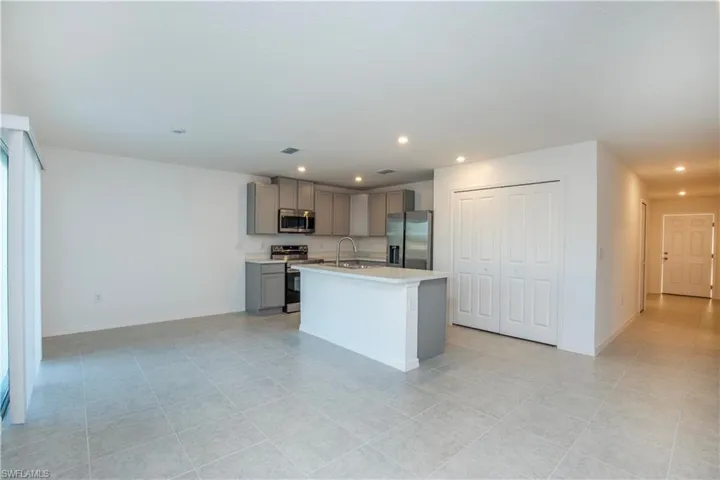 Kitchen featuring a kitchen island with sink, sink, gray cabinets, and stainless steel appliances