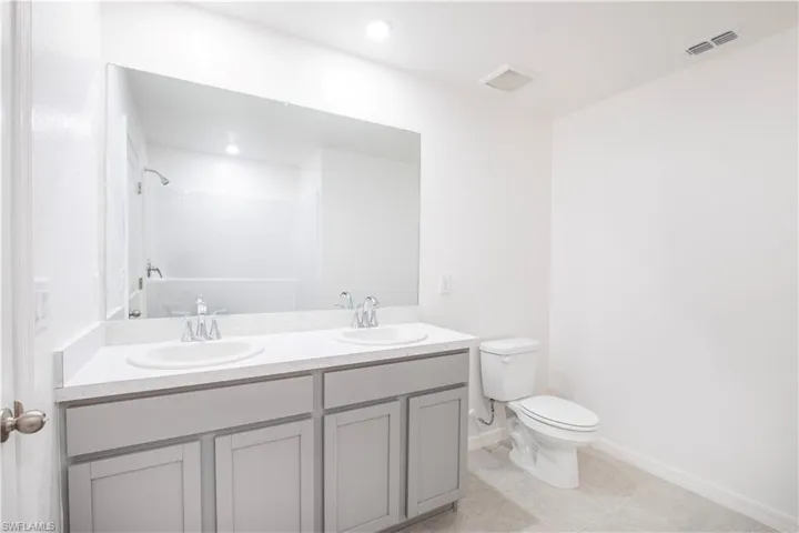 Bathroom with walk in shower, tile patterned floors, vanity, and toilet