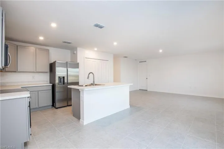 Kitchen featuring appliances with stainless steel finishes, gray cabinets, sink, and a center island with sink
