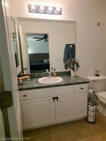 Ensuite bathroom with vanity, light tile patterned flooring, and a ceiling fan