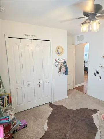 Carpeted bedroom with a closet and ceiling fan
