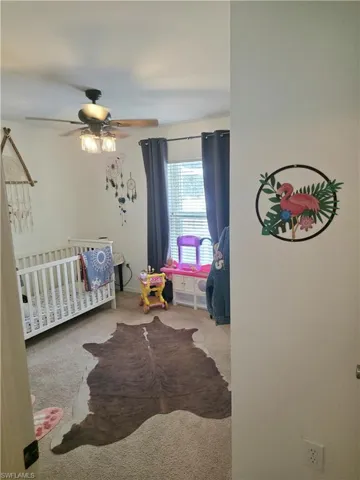 Bedroom with a crib, carpet flooring, and a ceiling fan