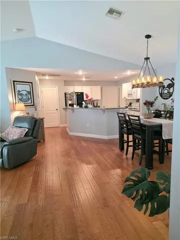 Dining area featuring light wood-type flooring, a chandelier, and vaulted ceiling