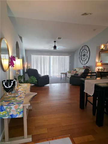 Living room featuring plenty of natural light, wood finished floors, ceiling fan, and lofted ceiling