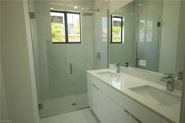 Full bathroom featuring double vanity, a sink, a marble finish shower, and marble finish floor