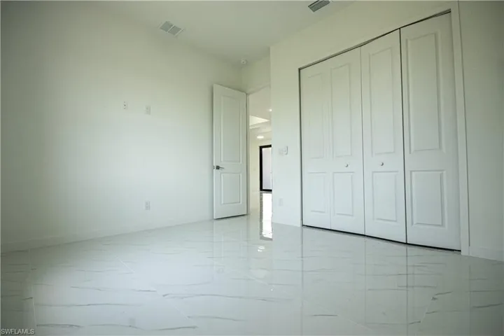 Unfurnished bedroom with visible vents, marble finish floor, baseboards, and a closet