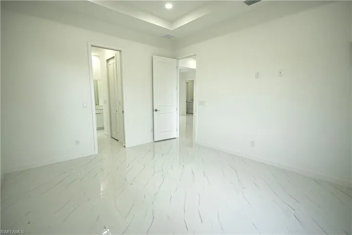 Unfurnished bedroom featuring connected bathroom, marble finish floor, recessed lighting, baseboards, and visible vents