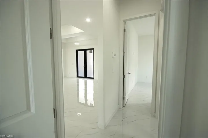 Hall with baseboards, recessed lighting, and marble finish floor