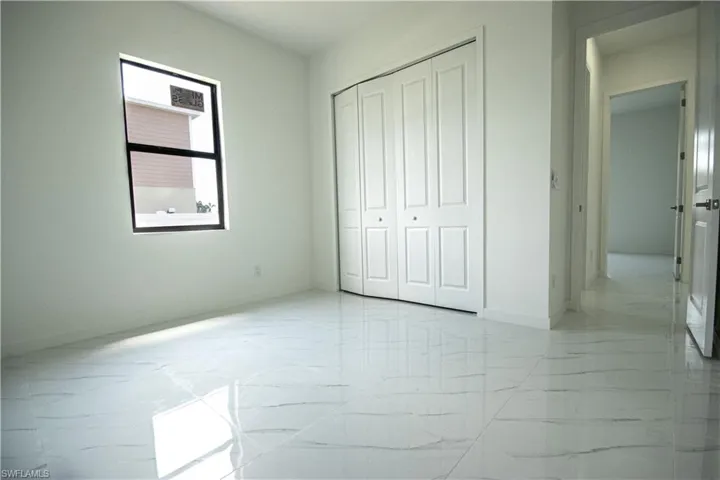 Unfurnished bedroom with baseboards, marble finish floor, and a closet