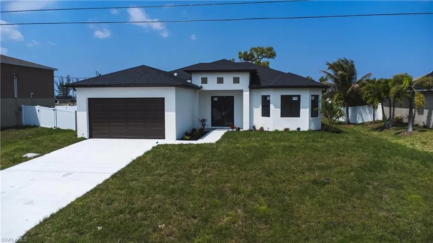 View of front of house featuring an attached garage, stucco siding, a front yard, and fence
