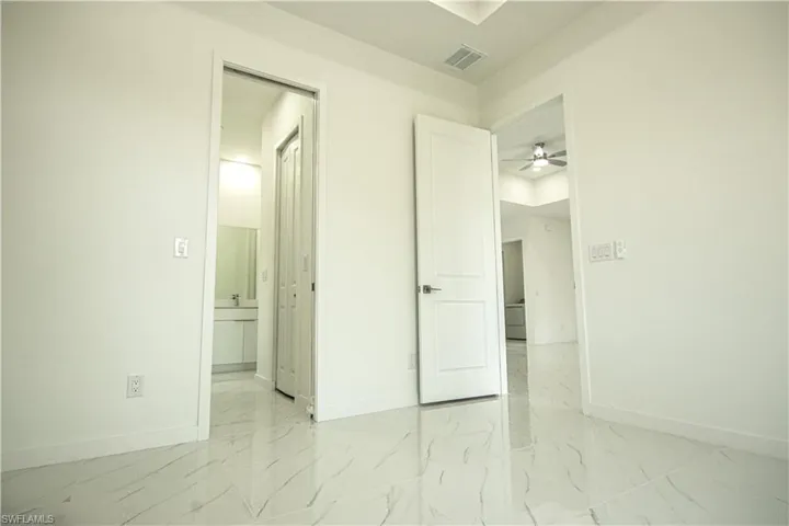 Unfurnished bedroom with visible vents, marble finish floor, ensuite bathroom, and baseboards