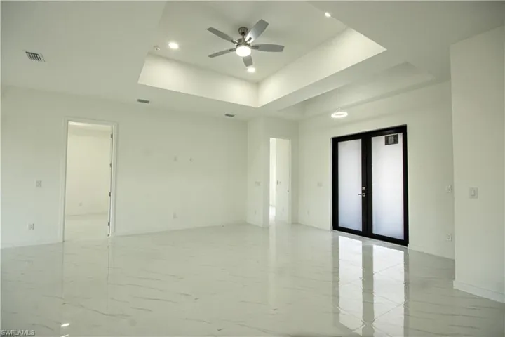 Unfurnished room with visible vents, marble finish floor, ceiling fan, and a tray ceiling