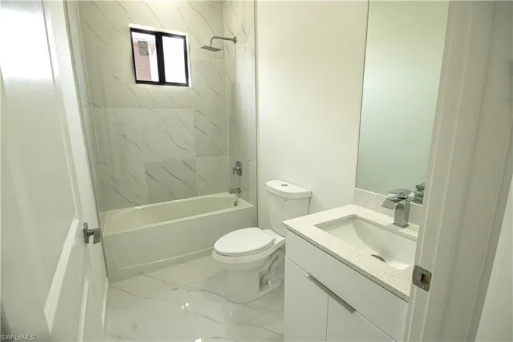 Bathroom with vanity, shower / bathing tub combination, toilet, and marble finish floor