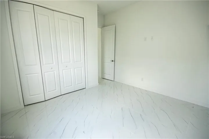 Unfurnished bedroom featuring baseboards, marble finish floor, and a closet
