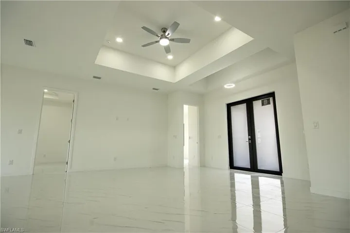 Unfurnished room featuring ceiling fan, a raised ceiling, french doors, recessed lighting, and visible vents