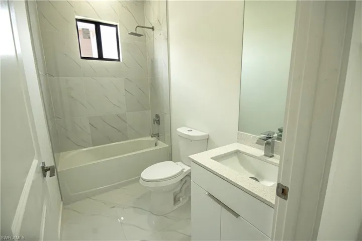 Bathroom with vanity, shower / bathtub combination, toilet, and marble finish floor