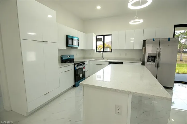Kitchen featuring appliances with stainless steel finishes, a sink, marble finish floor, and modern cabinets