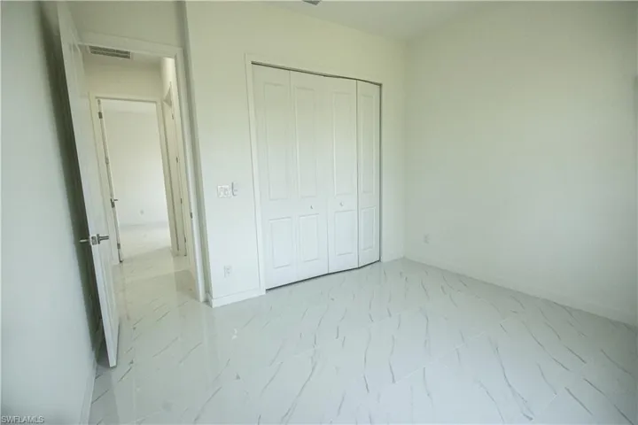 Unfurnished bedroom with baseboards, visible vents, marble finish floor, and a closet