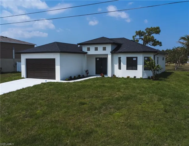 Prairie-style home featuring a garage, stucco siding, concrete driveway, and a front lawn