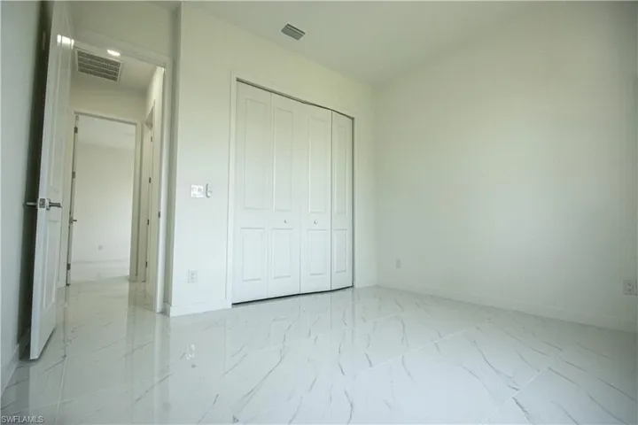 Unfurnished bedroom with baseboards, visible vents, and marble finish floor