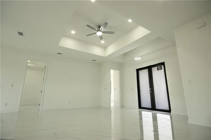 Unfurnished room featuring ceiling fan, french doors, visible vents, a raised ceiling, and recessed lighting