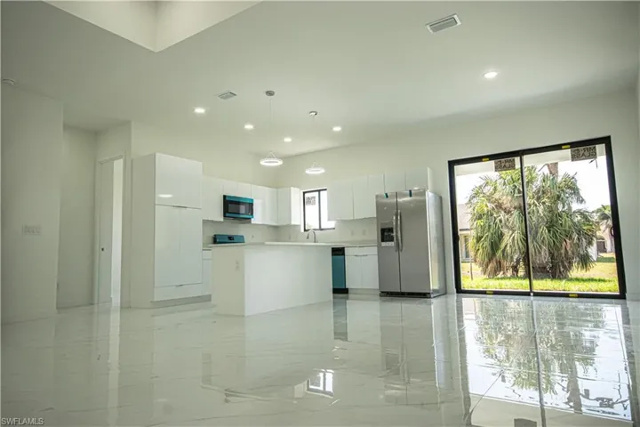 Kitchen featuring stainless steel refrigerator with ice dispenser, white cabinetry, a wealth of natural light, and visible vents