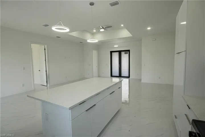 Kitchen with white cabinetry, open floor plan, visible vents, and marble finish floor