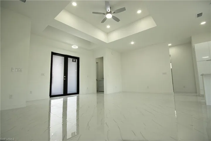 Spare room with ceiling fan, visible vents, marble finish floor, a tray ceiling, and recessed lighting