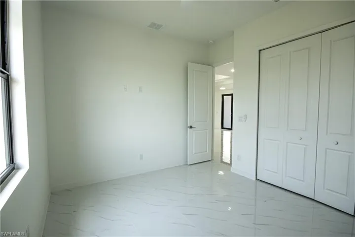 Unfurnished bedroom featuring baseboards, marble finish floor, visible vents, and a closet