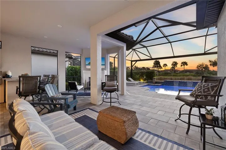 Patio terrace at dusk featuring pool water feature and a lanai