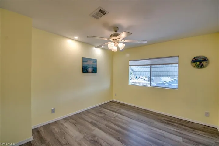 Spare room featuring wood finished floors, a ceiling fan, and recessed lighting