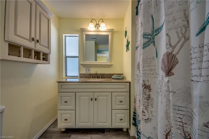 Full bath with vanity, wood finished floors, and a shower with shower curtain