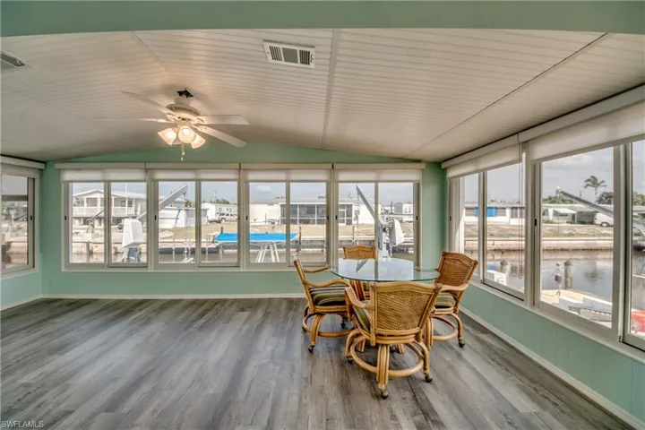 Sunroom / solarium with vaulted ceiling, wood finished floors, and a water view