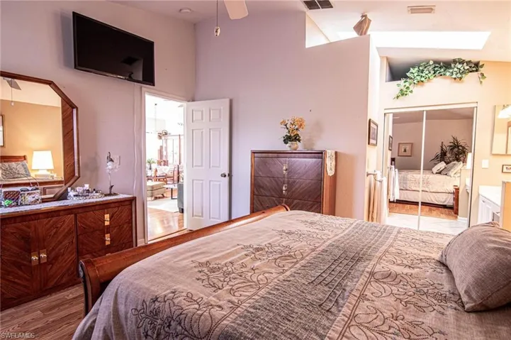 Bedroom featuring ceiling fan, a closet, lofted ceiling with skylight, and light hardwood / wood-style flooring