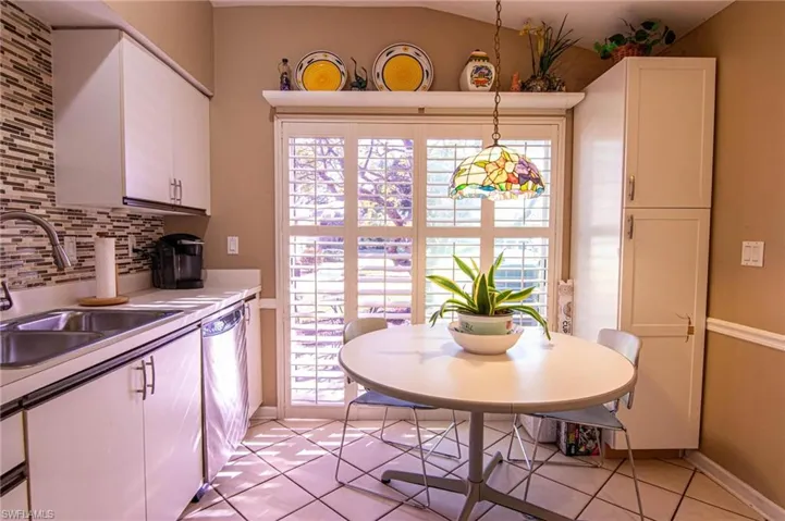 Kitchen with dishwasher, backsplash, white cabinets, sink, and hanging light fixtures