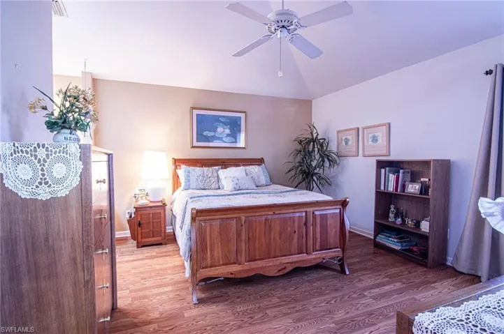 Bedroom with ceiling fan, lofted ceiling, and hardwood / wood-style flooring